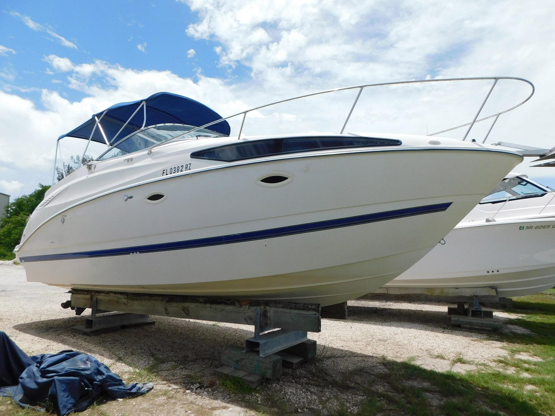 Bayliner 265 2007 Bayliner 265 boat on stands, blue canopy, clear sky background.
