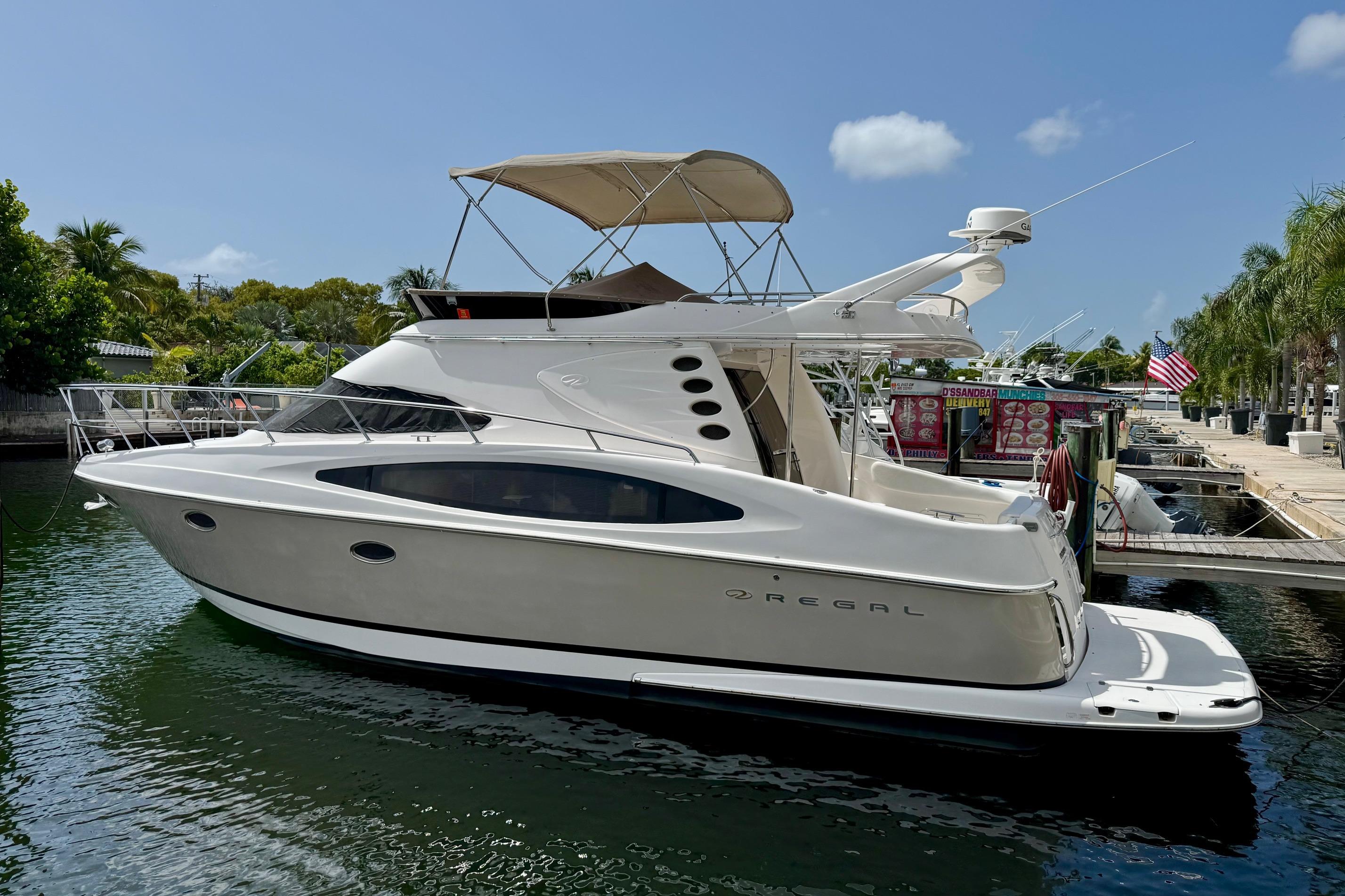 Regal 4080 Flybridge Luxury 2009 Regal 4080 yacht docked in a sunny marina setting.