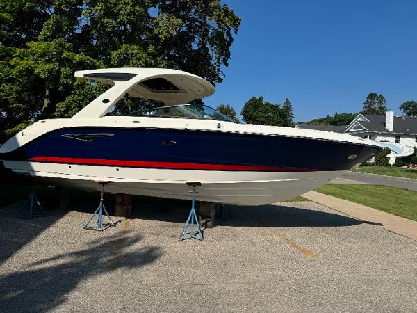 Sea Ray SLX 310 2024 Sea Ray SLX 310 boat on stands, blue and white design, sunny day.