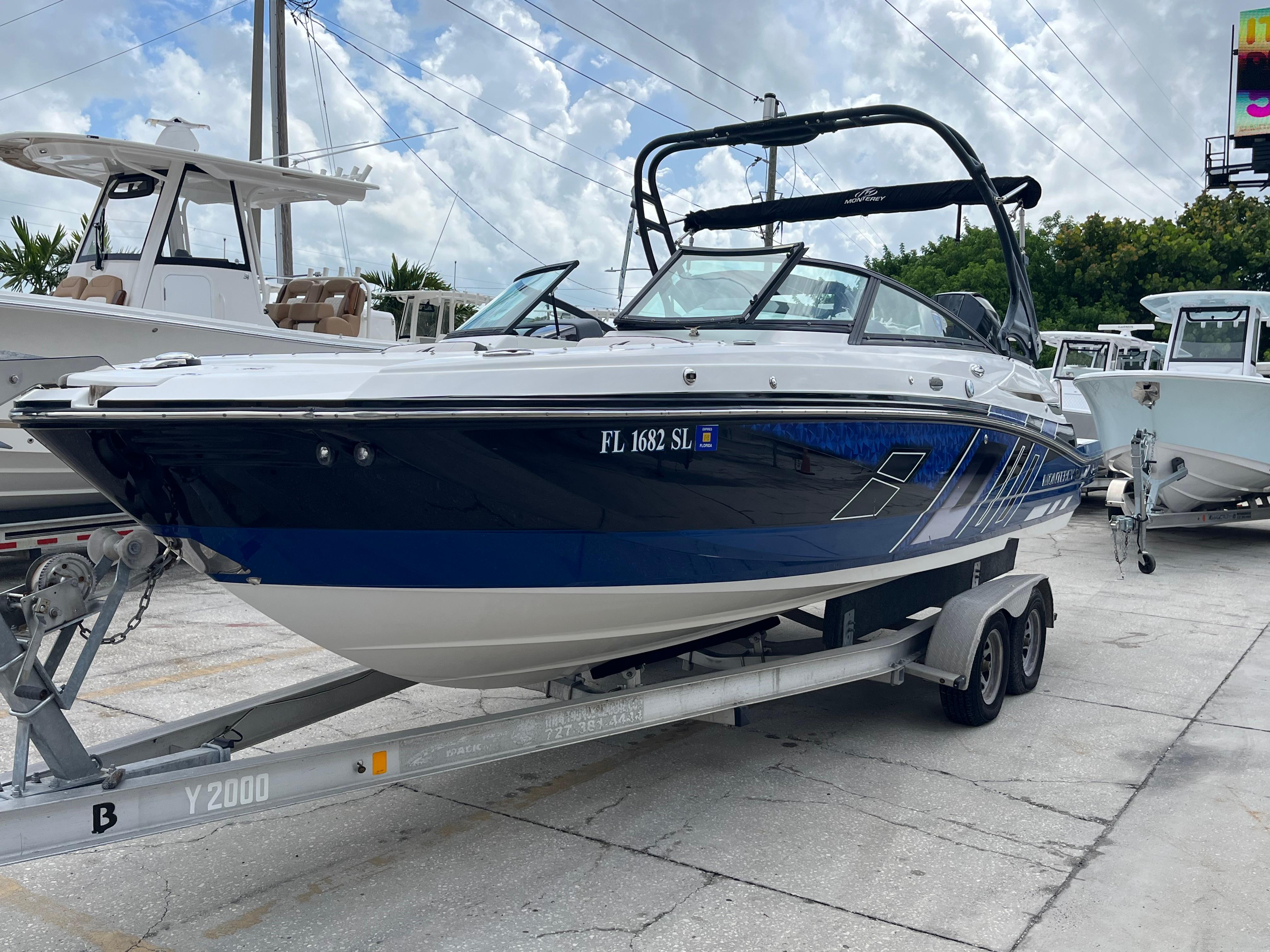 Monterey M45 2019 Monterey M45 boat on trailer, parked outdoors under cloudy sky.