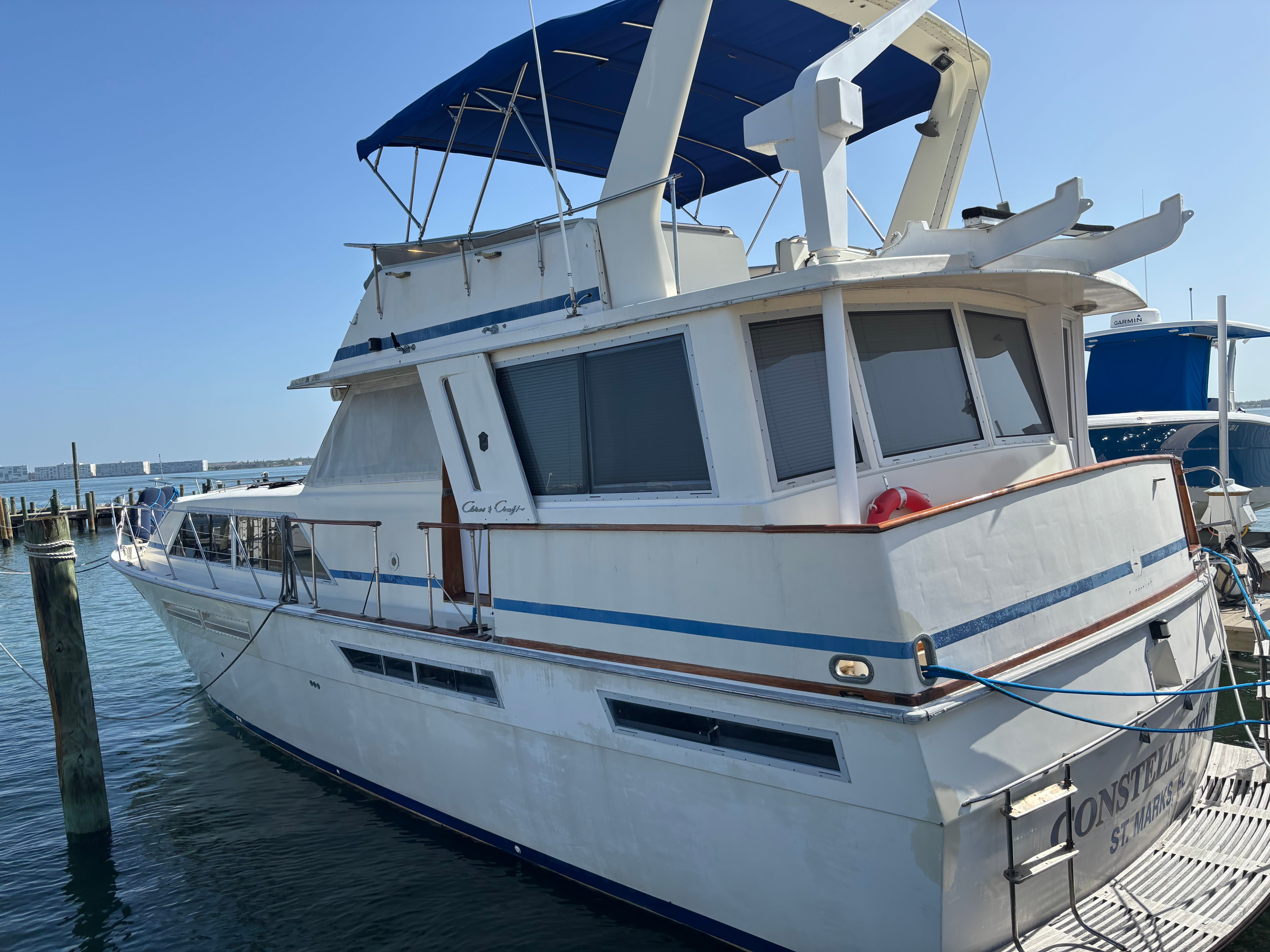 Chris-Craft Constallation 1986 Chris-Craft Constellation yacht docked at marina, featuring blue accents and spacious deck.