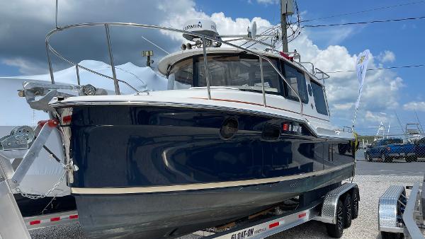 Ranger Tugs R-25 2022 Ranger Tugs R-25 boat on trailer, blue hull, docked outdoors under cloudy sky.