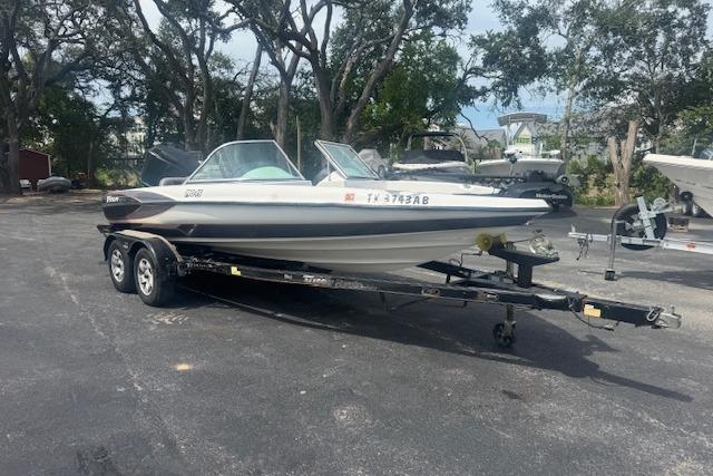 Triton 190-FS 2002 Triton 190-FS boat on trailer in outdoor setting with trees.
