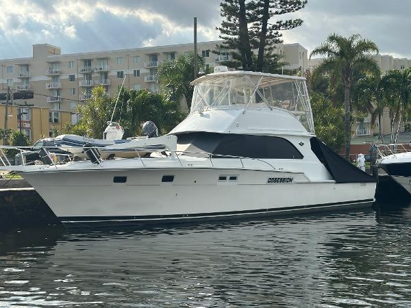 Bertram 46 Convertible 1985 Bertram 46 Convertible yacht docked near waterfront buildings and palm trees.