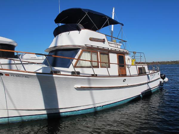 Monk 36 1986 Monk 36 boat with blue canopy, docked on calm water under clear sky.