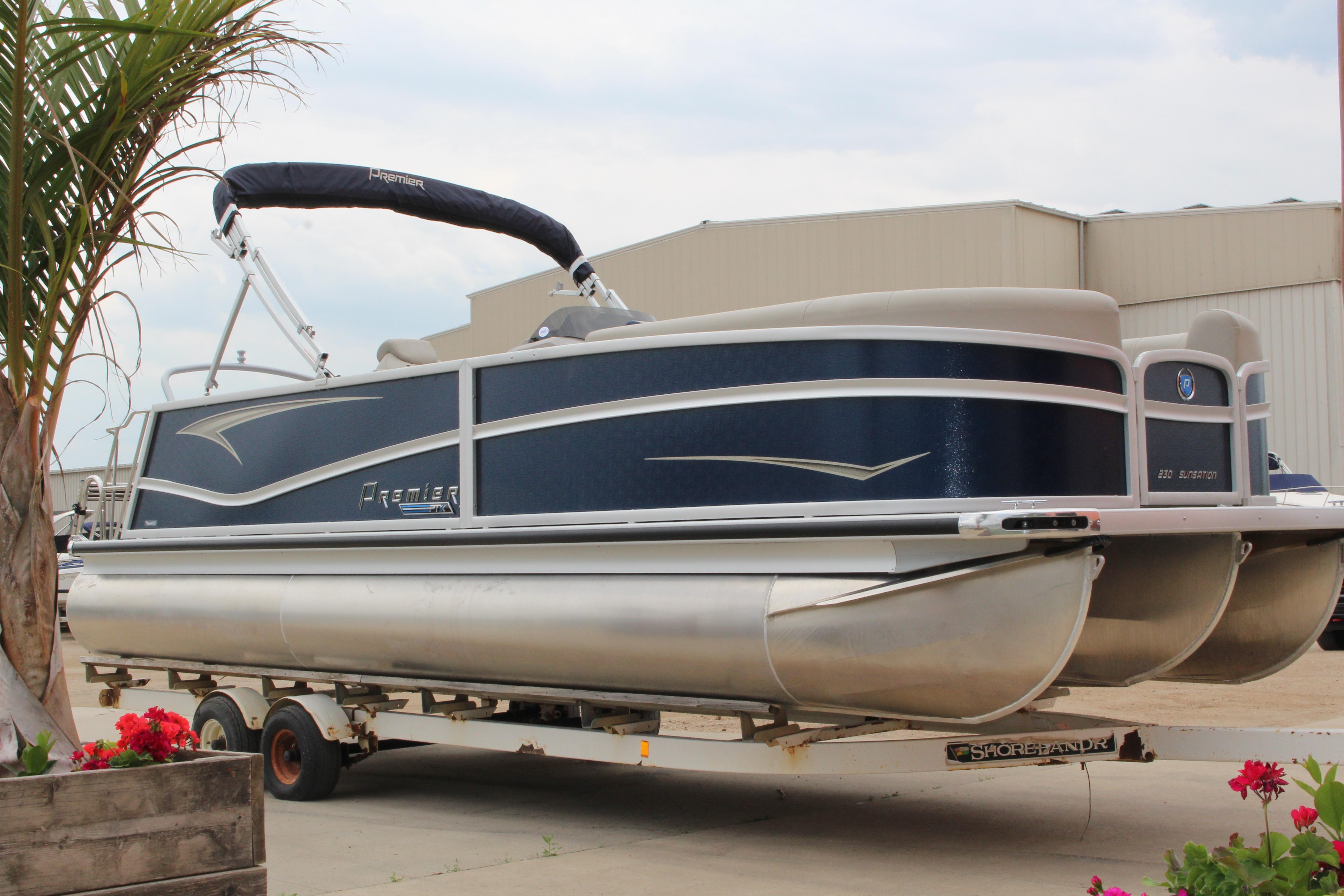 Premier Sunsation 230 2022 Premier Sunsation 230 pontoon boat on trailer, outdoor setting with palm and flowers.