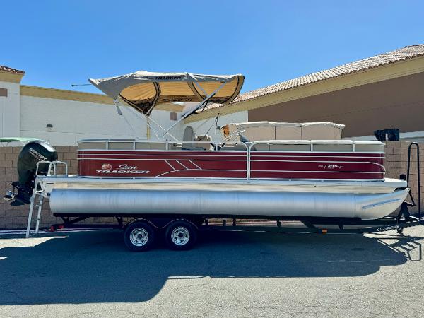 Sun Tracker Party Barge 24 DLX 2021 Sun Tracker Party Barge 24 DLX pontoon boat on trailer, parked outdoors.