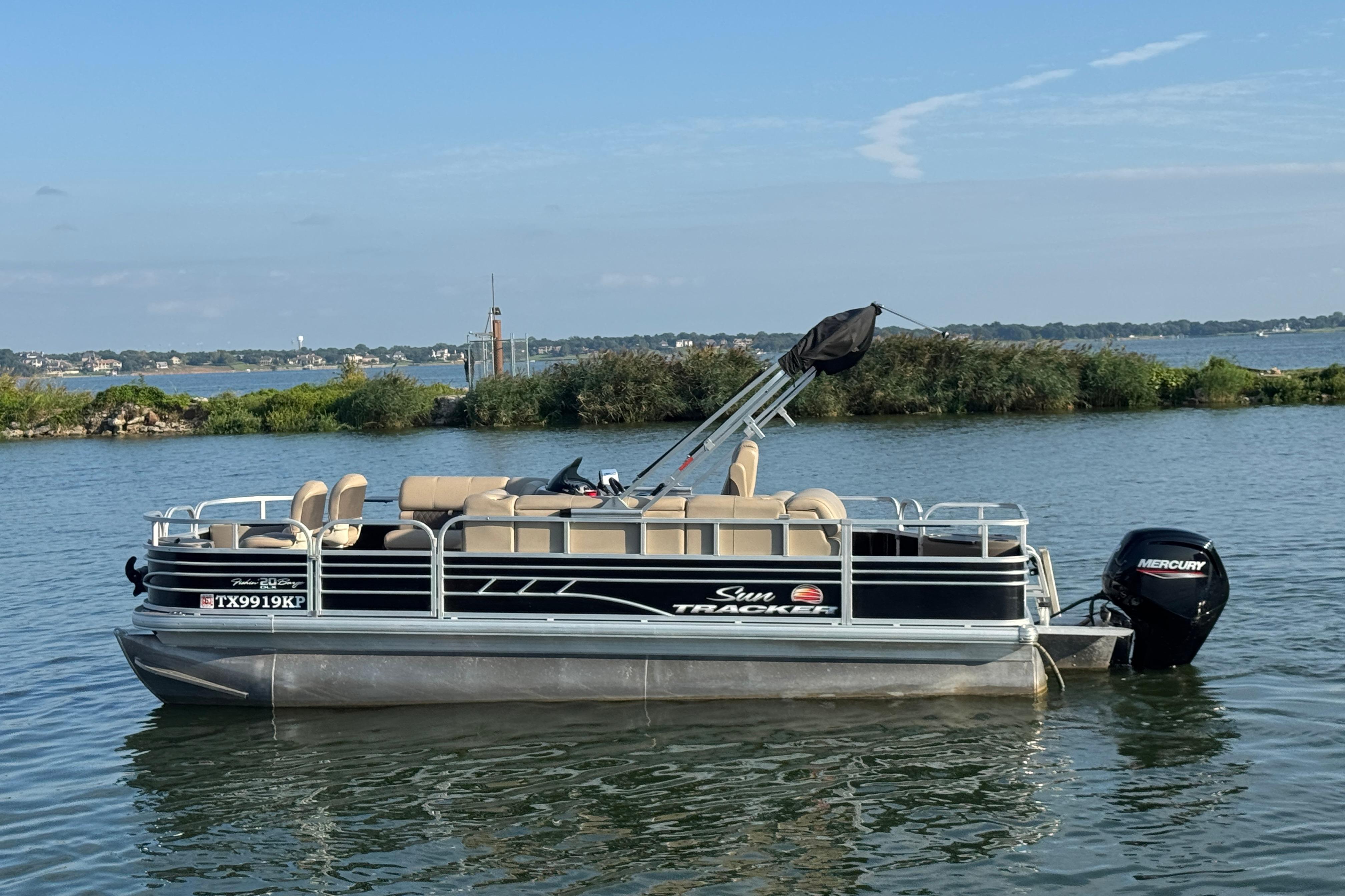Sun Tracker Fishin' Barge 20 DLX 2022 Sun Tracker Fishin' Barge 20 DLX pontoon boat on a serene lake.