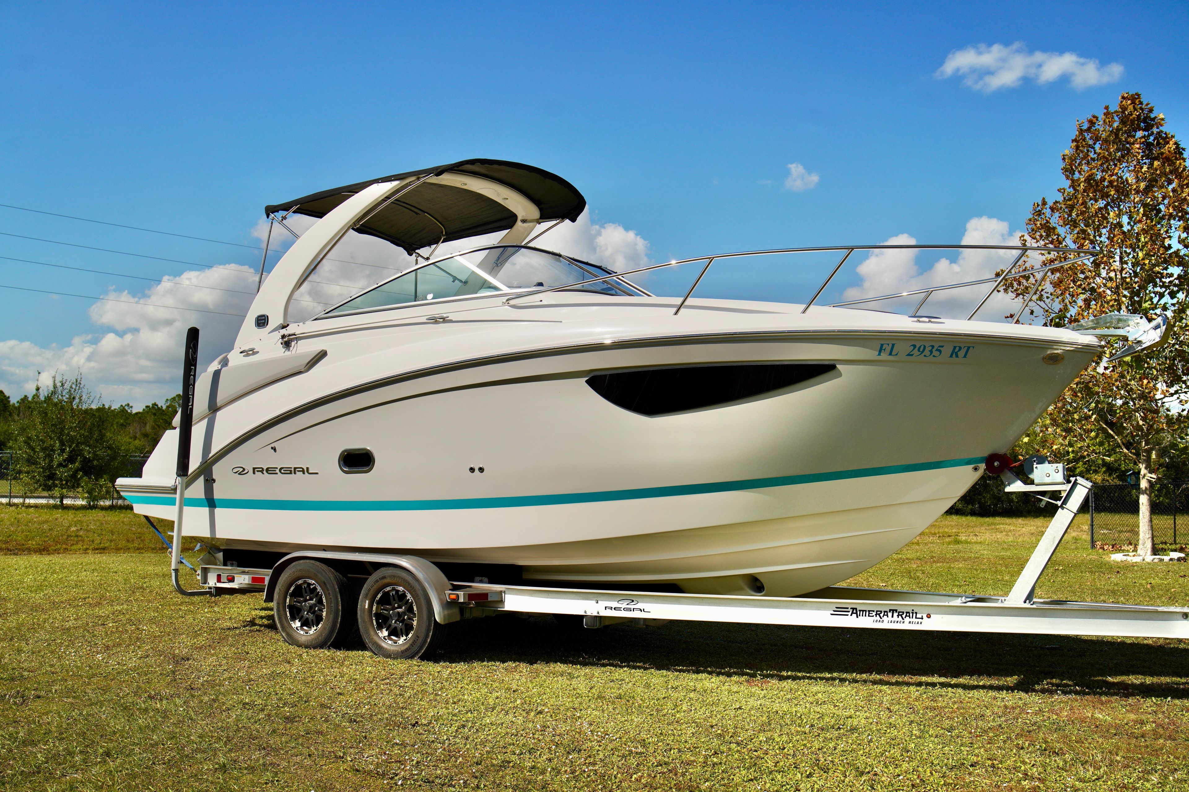 Regal 26 Express 2019 Regal 26 Express boat on trailer, parked on grass under clear blue sky.