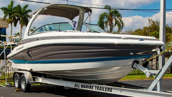 Crownline 290 XSS 2023 Crownline 290 XSS boat on trailer, parked outdoors with palm trees in background.