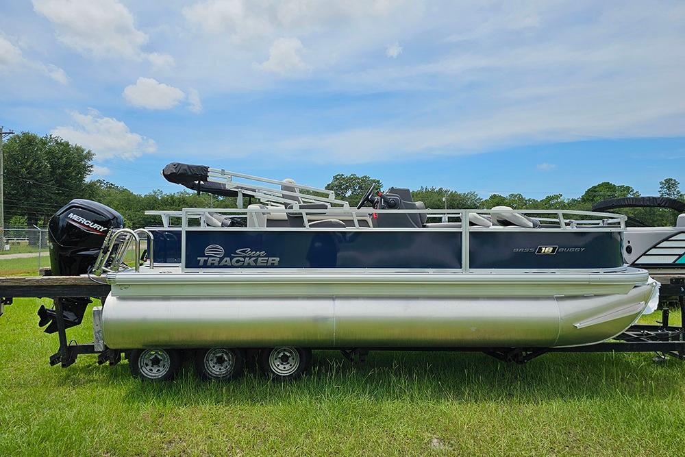Sun Tracker Bass Buggy 18 DLX 2026 Sun Tracker Bass Buggy 18 DLX pontoon boat on grassy field.
