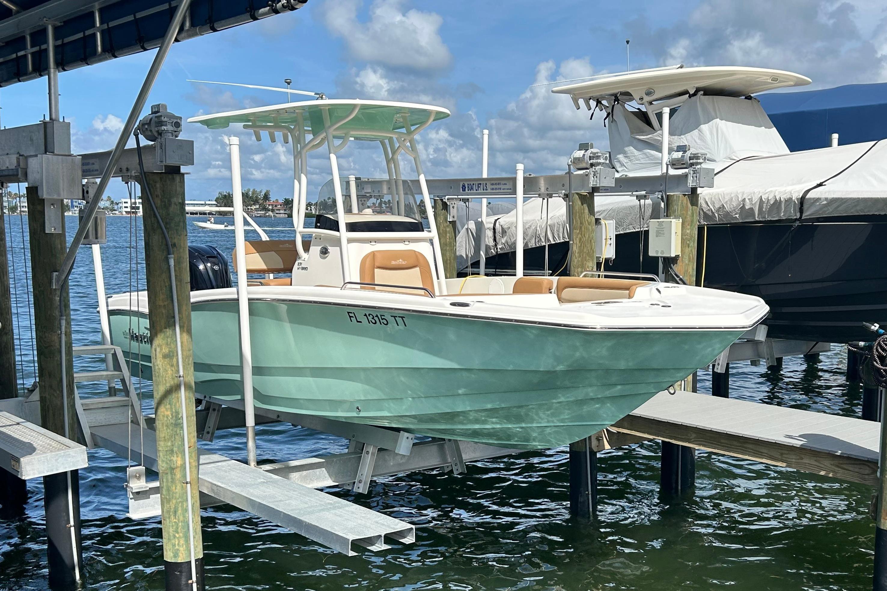 NauticStar 231 Hybrid 2023 NauticStar 231 Hybrid boat docked on lift, clear sky background.