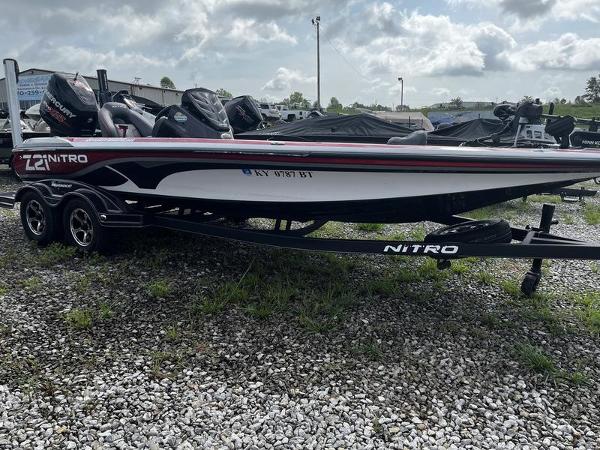 Nitro Z21 2018 Nitro Z21 boat on trailer, parked on gravel lot under cloudy sky.