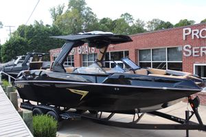 Tigé 24RZX 2026 Tigé 24RZX boat displayed at dealership, sleek black design, parked on trailer.