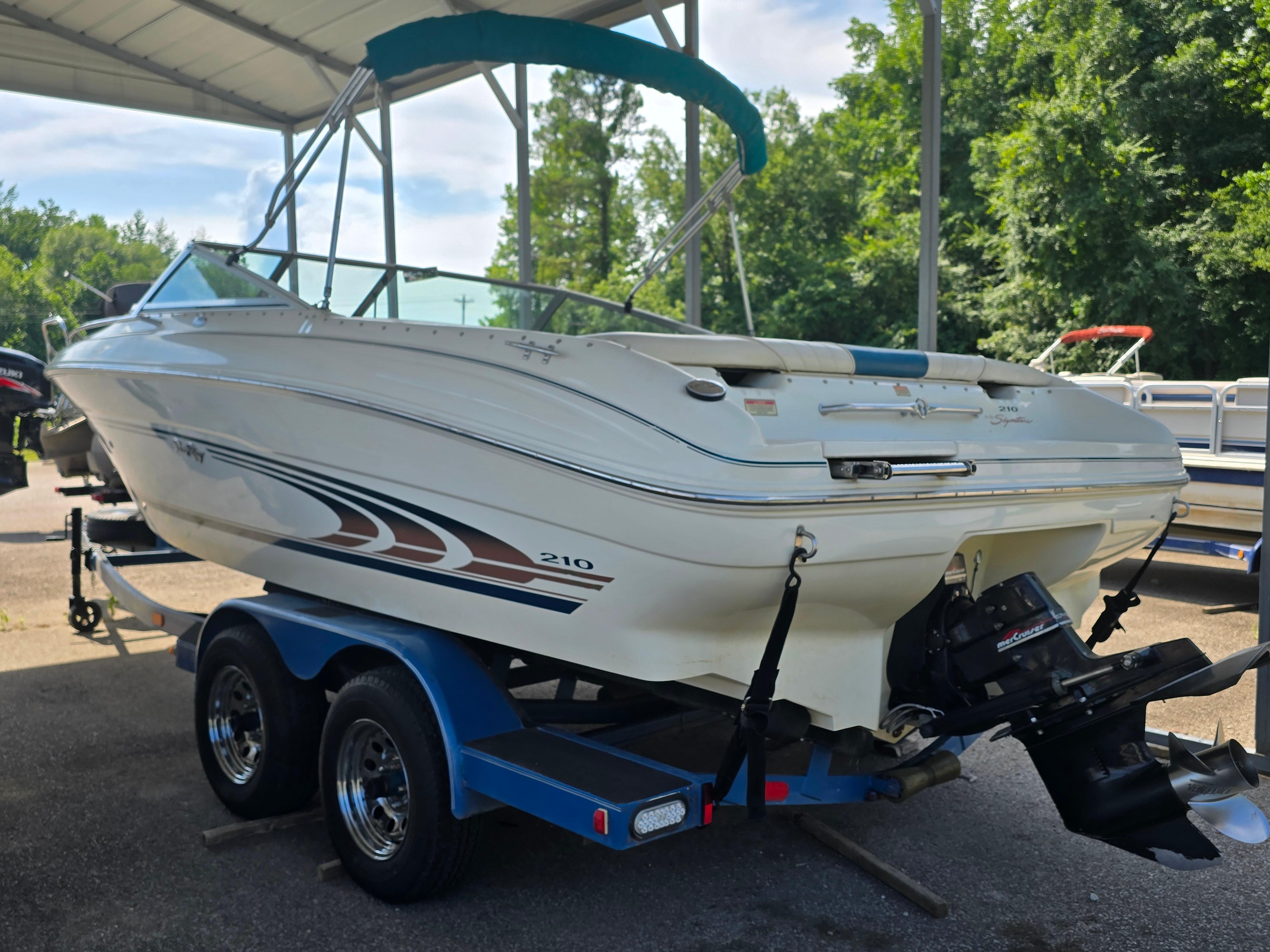 Sea Ray 210 Bow Rider 1998 Sea Ray 210br boat on trailer under canopy, surrounded by trees.