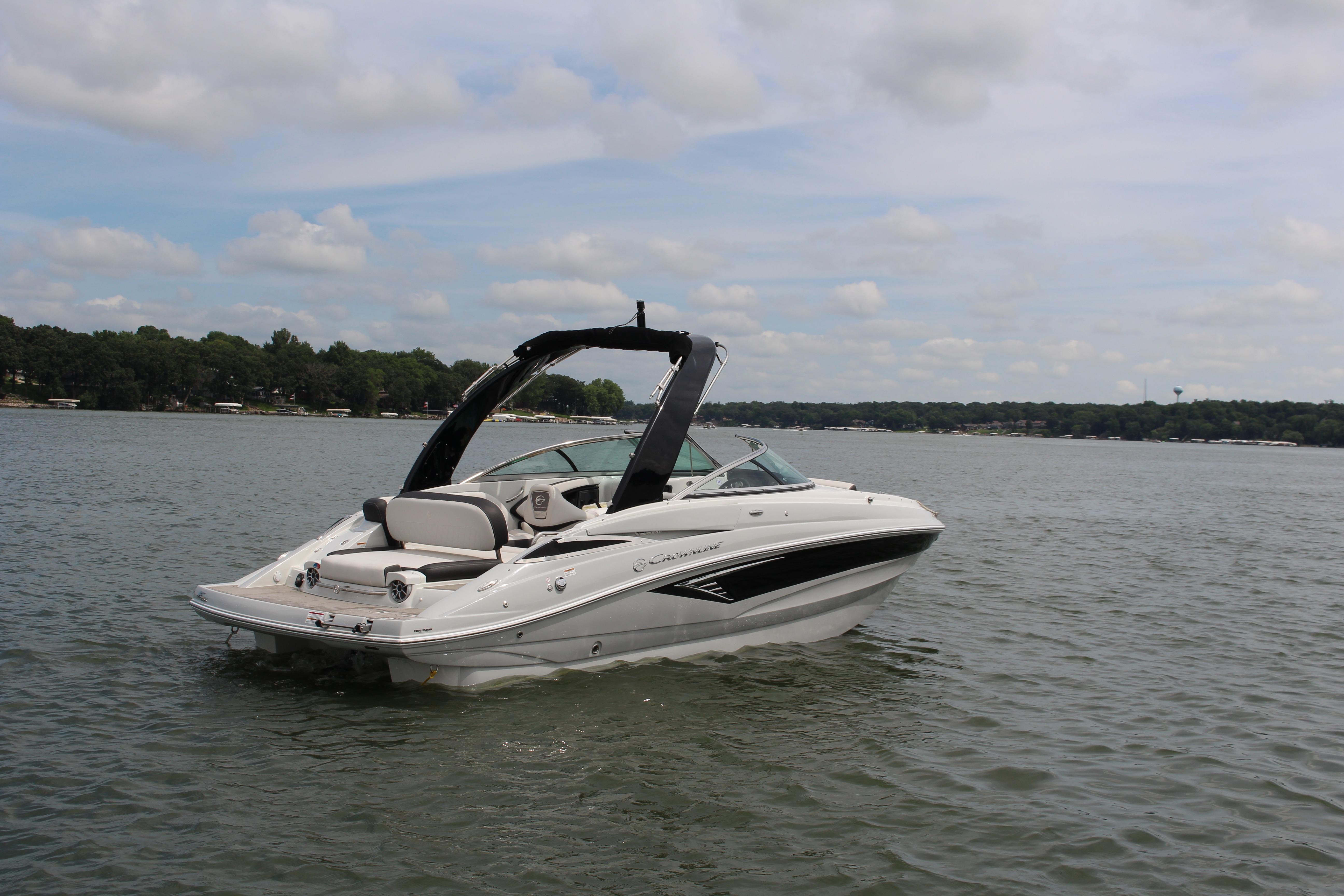 Crownline E235 2023 Crownline E235 boat on a calm lake under a partly cloudy sky.