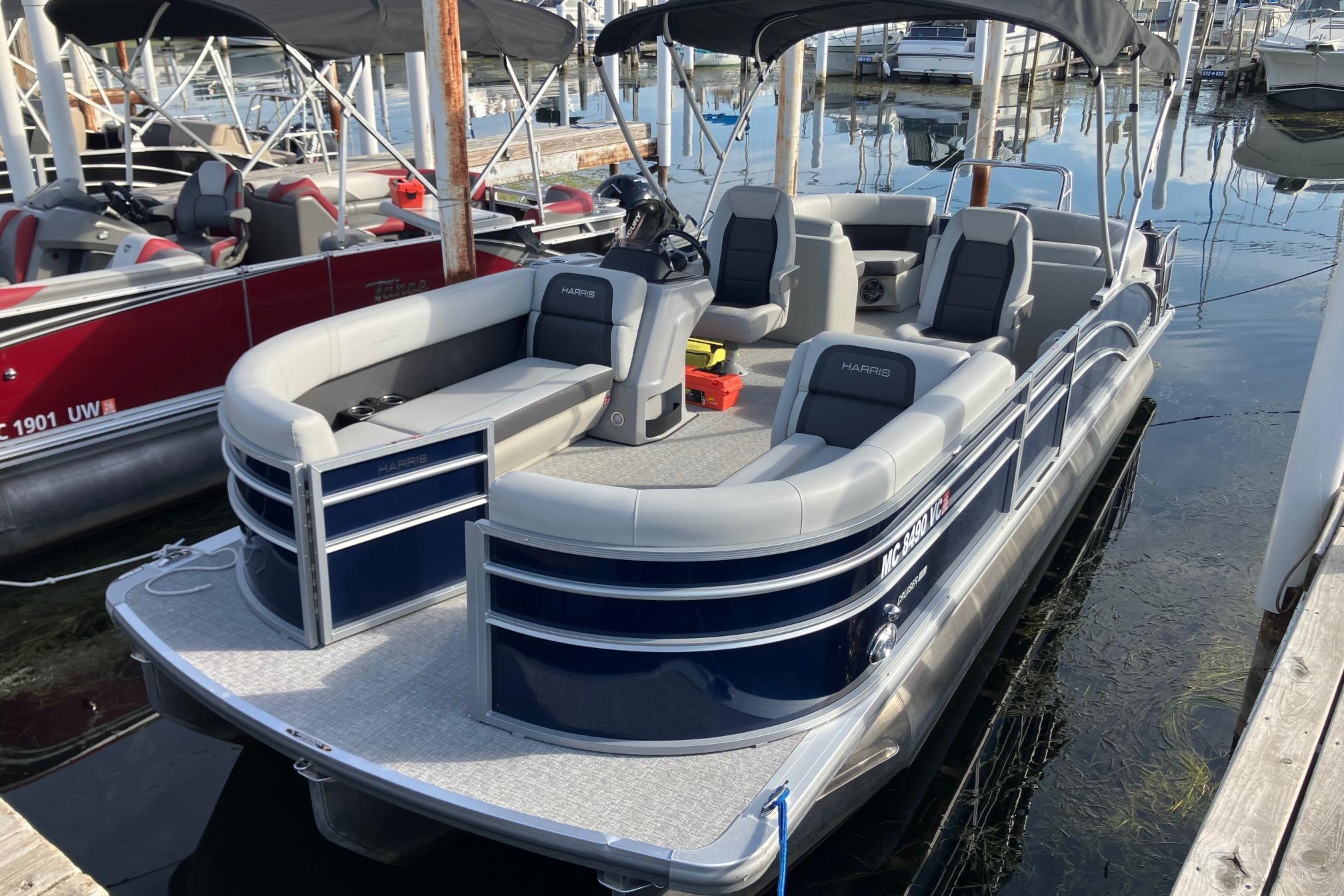 Harris Cruiser 230 2025 Harris Cruiser 230 pontoon boat docked at marina, featuring spacious seating and sleek design.