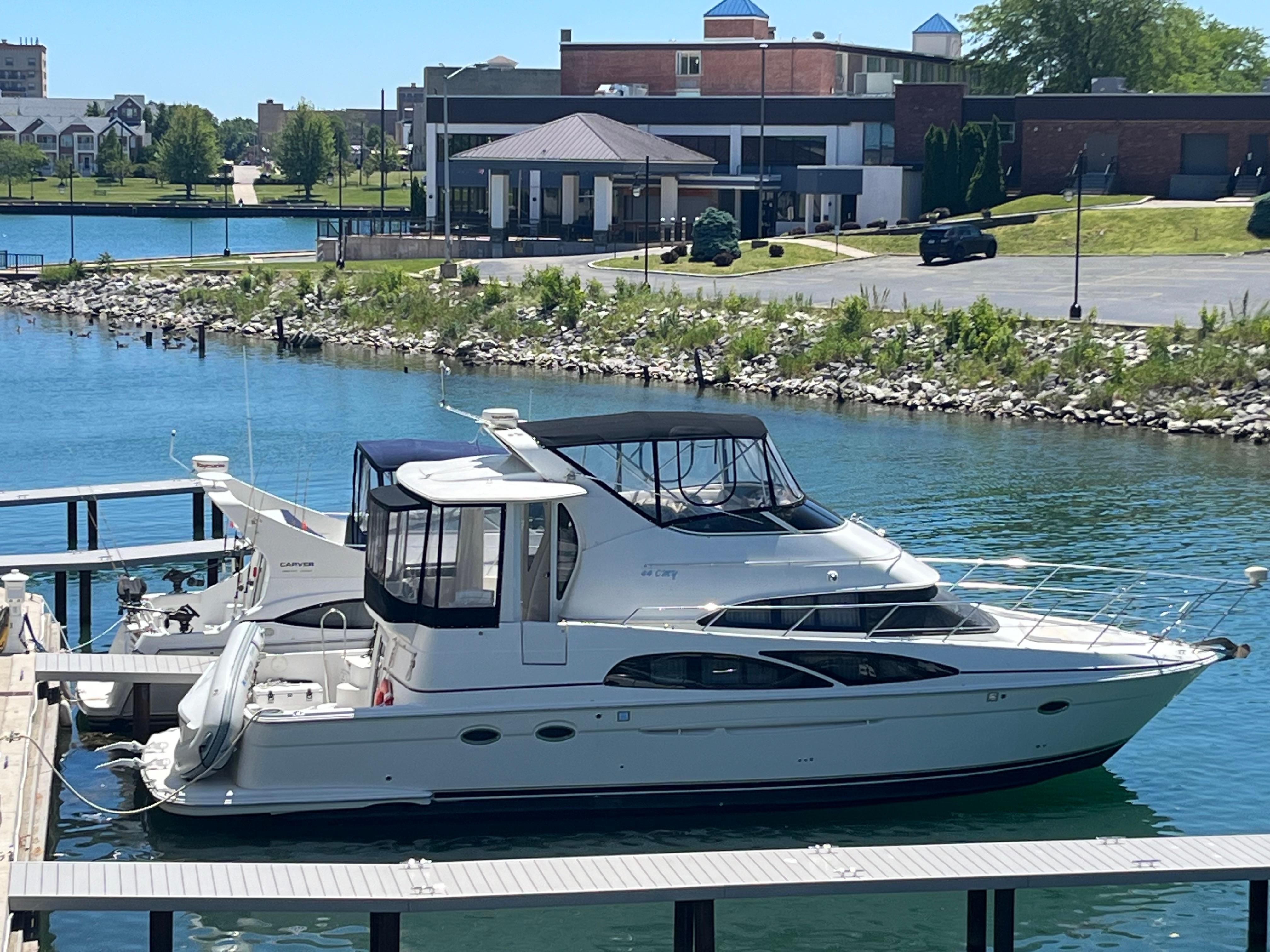 Carver 44 CMY 2005 Carver 44 CMY yacht docked in a marina with scenic waterfront view.