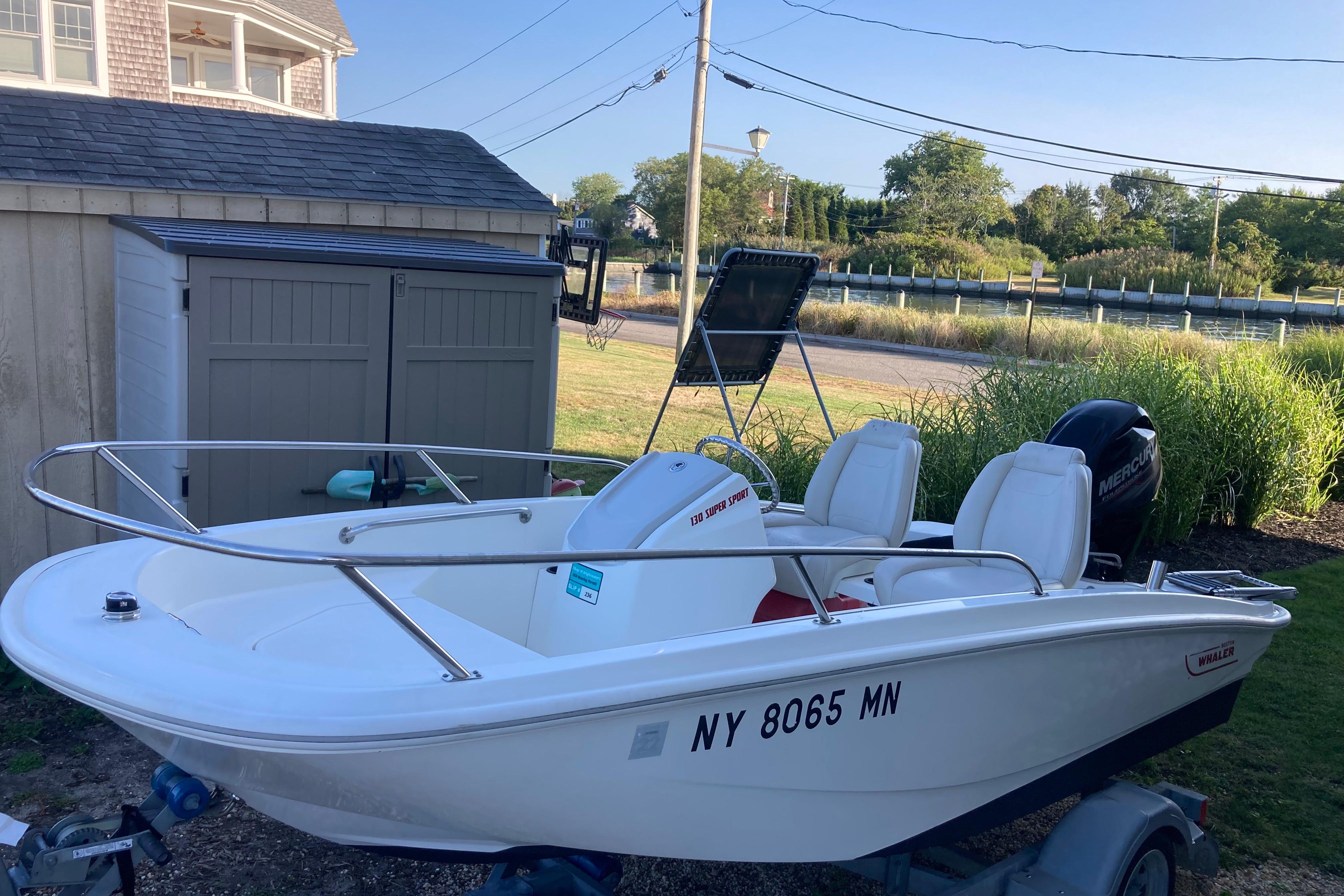 Boston Whaler 130 Super Sport 2019 Boston Whaler 130 Super Sport boat parked near a shed, ready for adventure.
