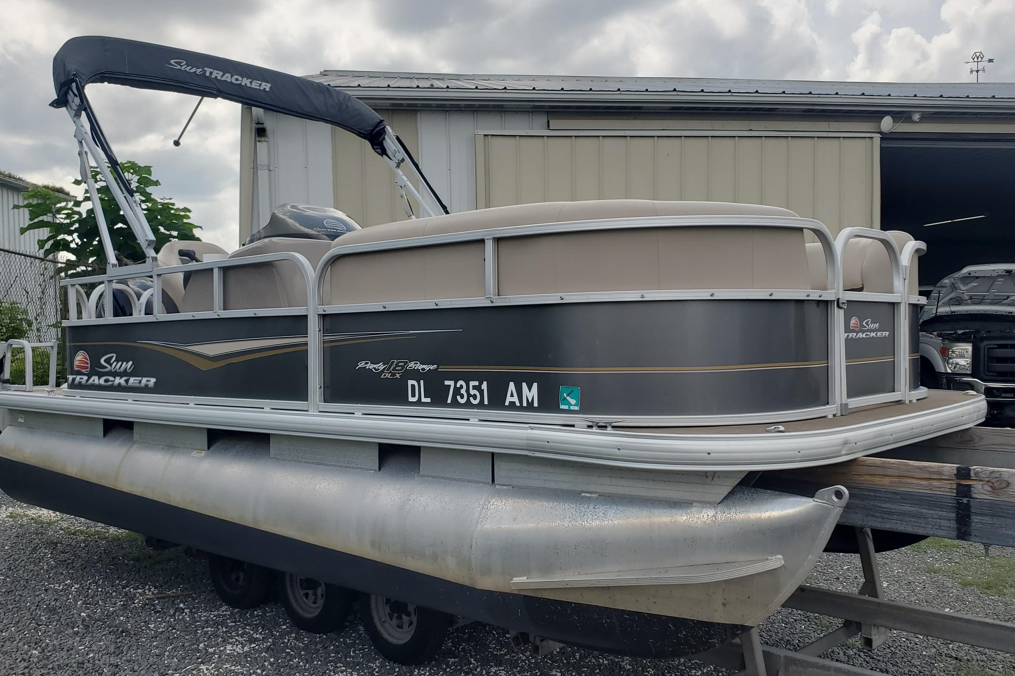 Sun Tracker party barge 180 dlx 2020 SUNTRACKER Party Barge 180 DLX pontoon boat on trailer, parked outdoors.