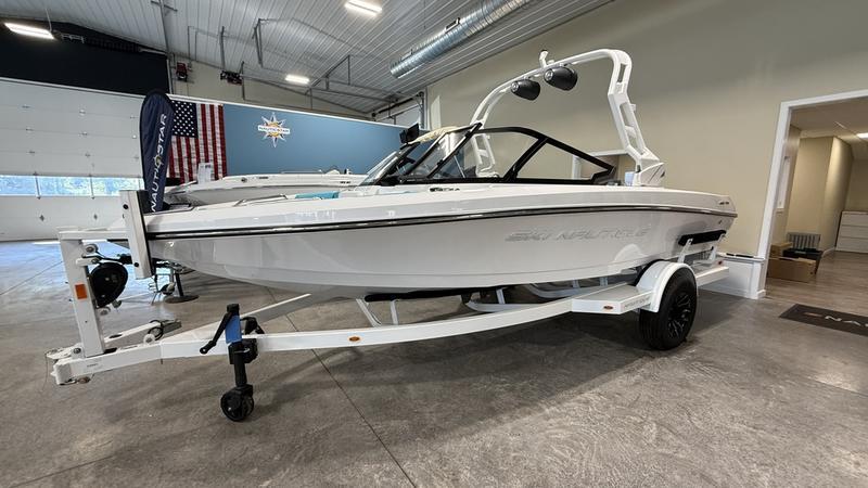 Nautique ski 200 2025 Nautique Ski 200 boat in showroom, white exterior, on trailer.