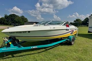 Baja 188 Islander 1996 Baja 188 Islander boat on trailer, parked on grass under a clear blue sky.
