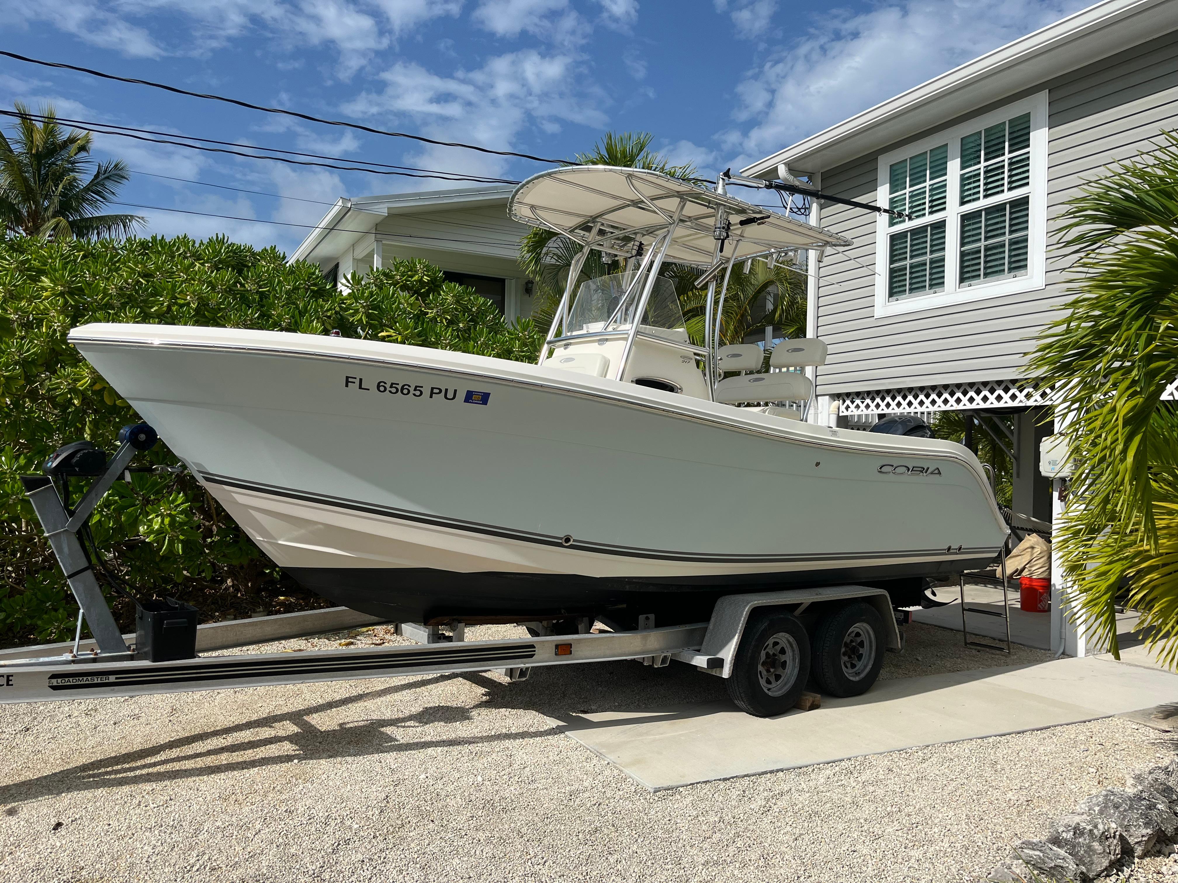 Cobia 217 Center Console 2014 Cobia 217 Center Console boat on trailer, parked beside a house.