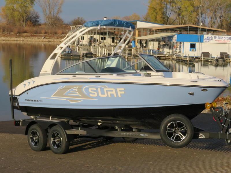 Chaparral 21 Surf 2024 Chaparral 21 Surf boat on trailer by marina, showcasing sleek design and modern features.