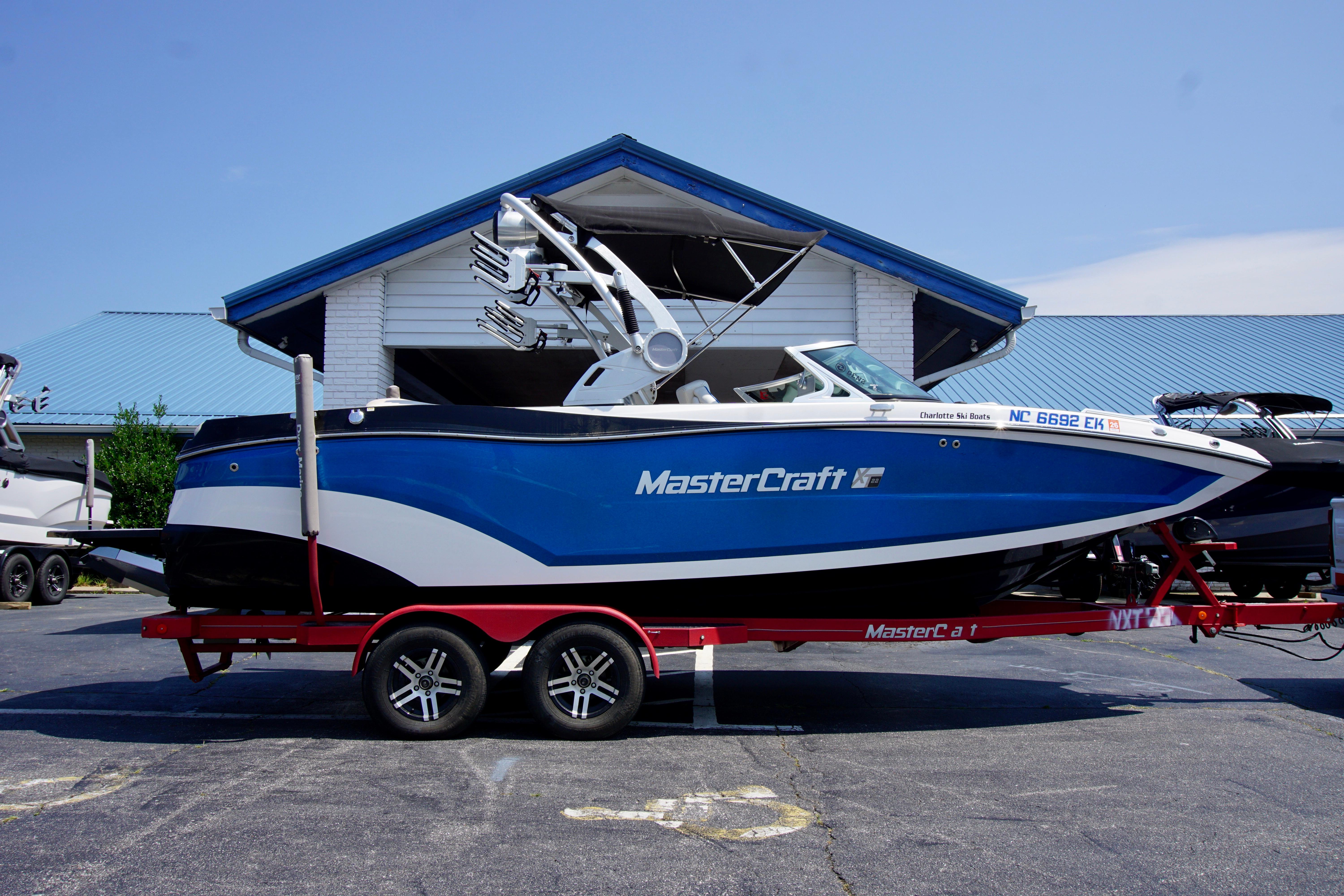 MasterCraft XT22 2018 MasterCraft XT22 boat on red trailer, parked outside a building.