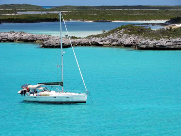 Beneteau 393 2003 Beneteau 393 sailboat anchored in clear turquoise waters near rocky shoreline.