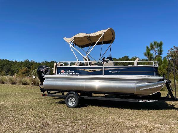 Sun Tracker Bass Buggy 18 DLX 2025 Sun Tracker Bass Buggy 18 DLX pontoon boat on trailer, parked on grass.