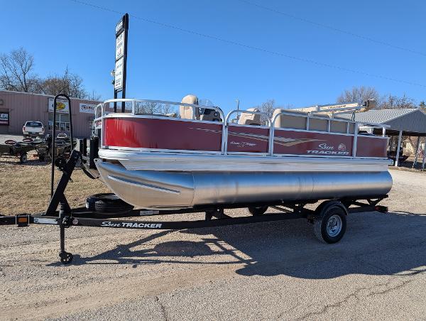 Sun Tracker Bass Buggy 18 DLX 2025 Sun Tracker Bass Buggy 18 DLX pontoon boat on trailer, parked outdoors.