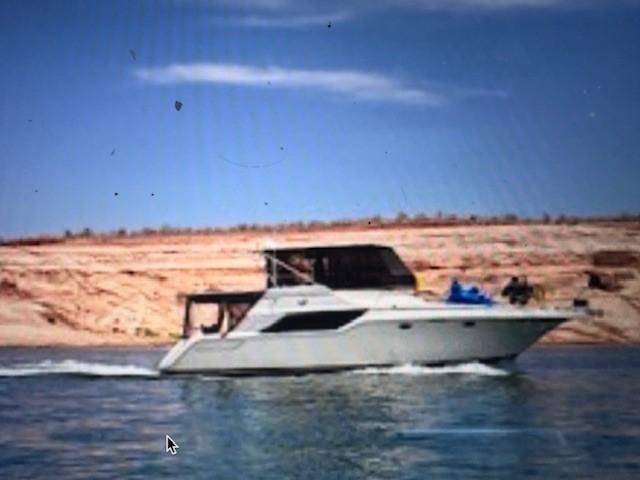 Cruisers Yachts 4280 Express Bridge 1988 Cruisers Yachts 4280 Express Bridge on serene water with rocky shoreline backdrop.
