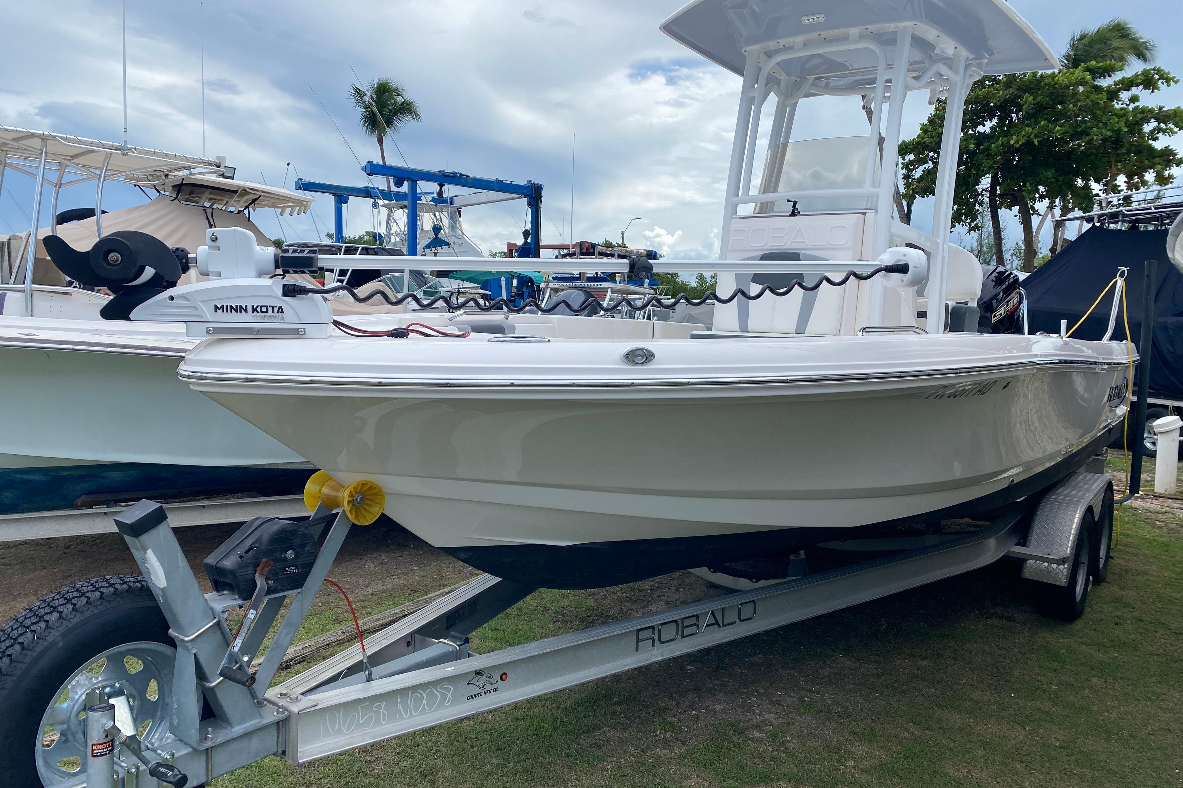 Robalo 226 Cayman 2023 Robalo 226 Cayman boat on trailer with Minn Kota motor, parked outdoors.
