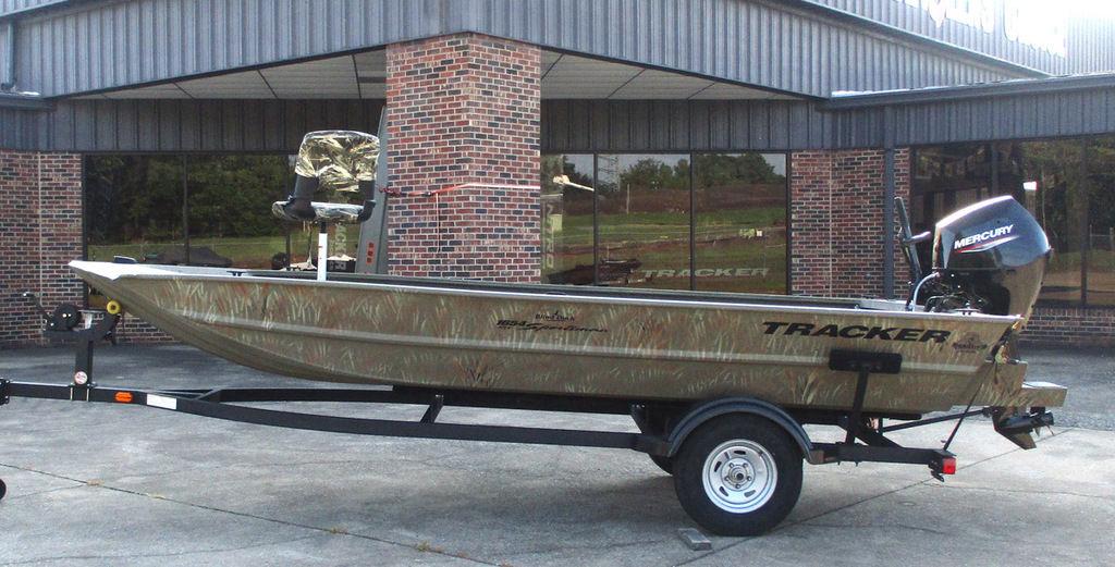 Tracker Grizzly 1654 T Sportsman 2025 Tracker GRIZZLY® 1654 T Sportsman boat on trailer, parked outside a building.