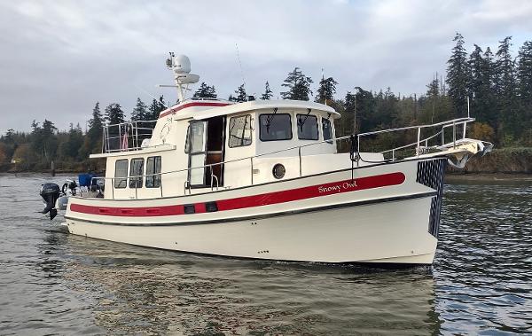 Nordic Tug 42 2000 Nordic Tug 42 boat on calm water with forested shoreline.