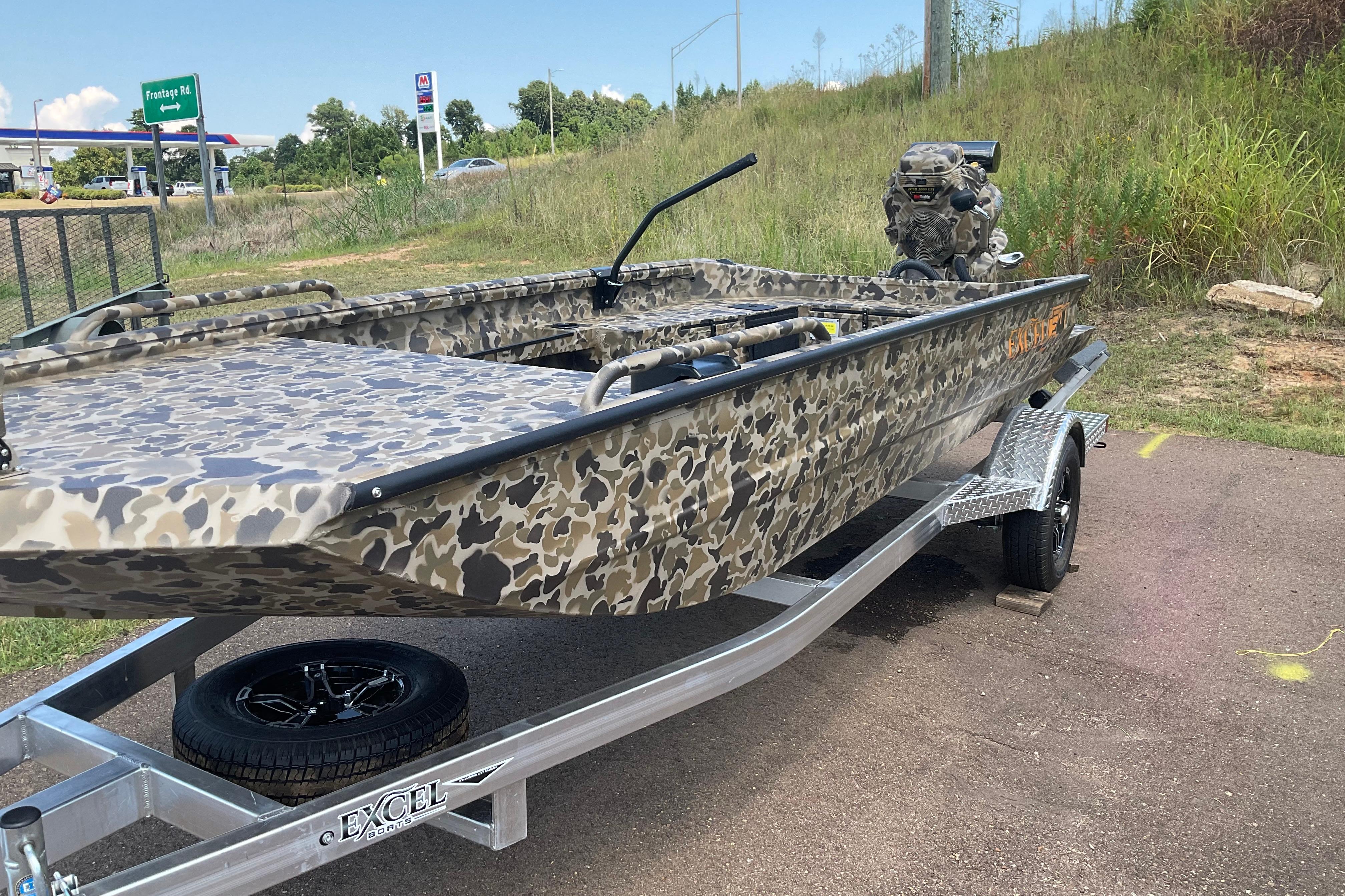 Excel 1754 F4 Shallow Water 2026 Excel 1751 F4 Shallow Water boat with camouflage design on a trailer.