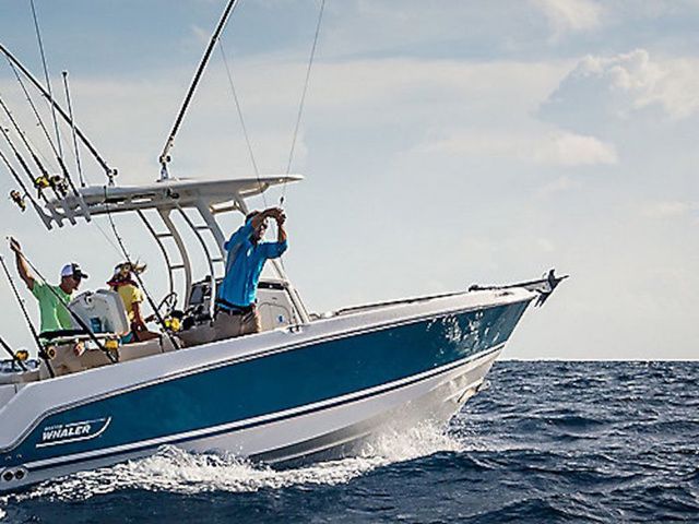 Boston Whaler 230 Outrage 2025 Boston Whaler 230 Outrage boat navigating ocean waves, featuring fishing rods and passengers.