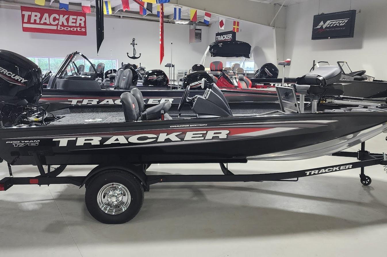 Tracker Pro Team 175 Crappie Edition 2025 Tracker Pro Team 175 Crappie Edition boat displayed in showroom with flags above.
