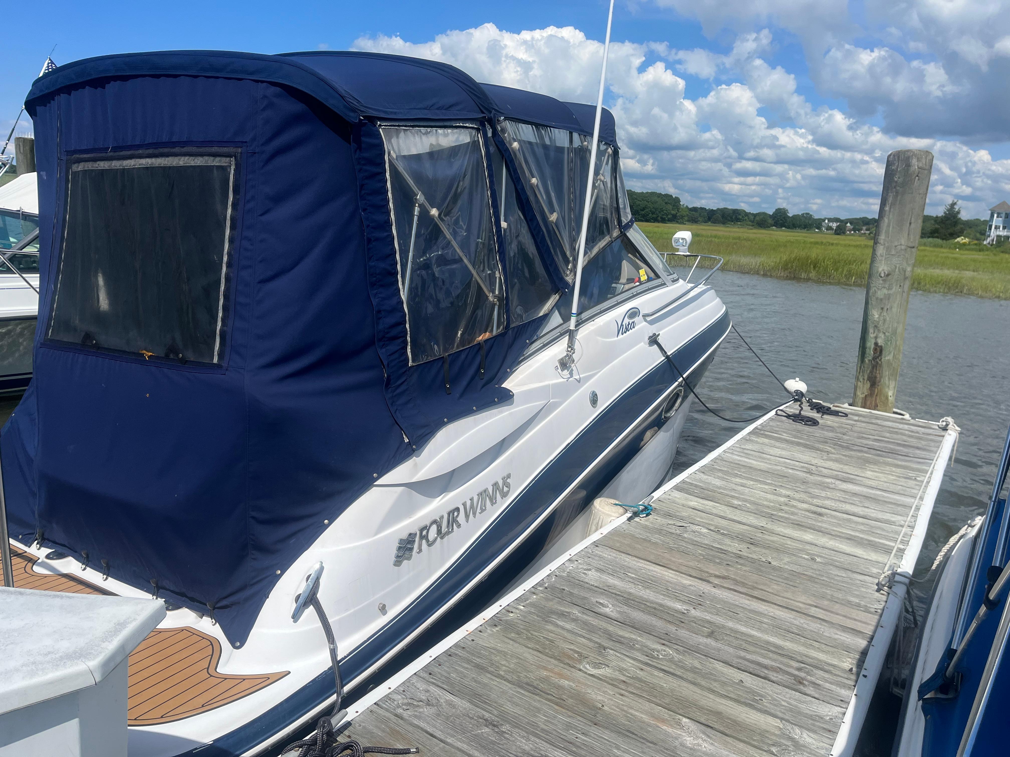 Four Winns 258 Vista 2007 Four Winns 258 Vista boat docked with blue canopy under cloudy sky.