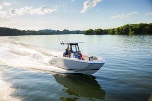 Yamaha Boats 255 FSH Sport H 2026 Yamaha Boats 255 FSH Sport H cruising on a serene lake under a clear sky.