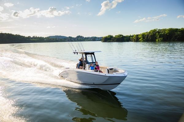 Yamaha Boats 255 FSH Sport H 2026 Yamaha Boats 255 FSH Sport H cruising on a serene lake under a clear sky.
