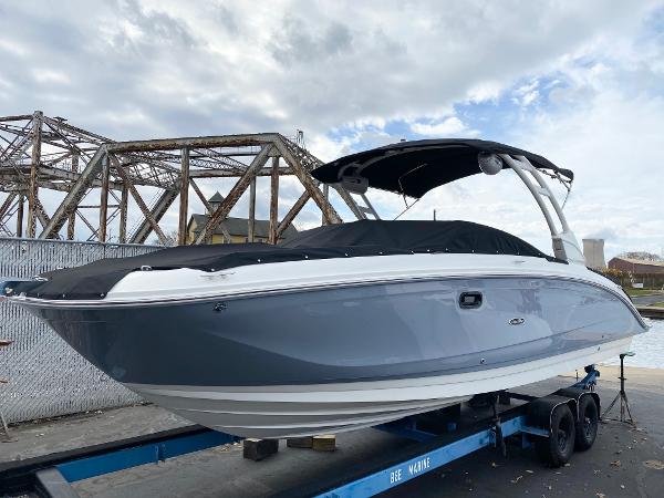 Sea Ray SDX 290 2021 Sea Ray SDX 290 boat on trailer, under cloudy sky near industrial bridge.