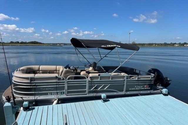 Sun Tracker Party Barge 22 DLX 2023 Sun Tracker Party Barge 22 DLX pontoon boat docked on a sunny day.