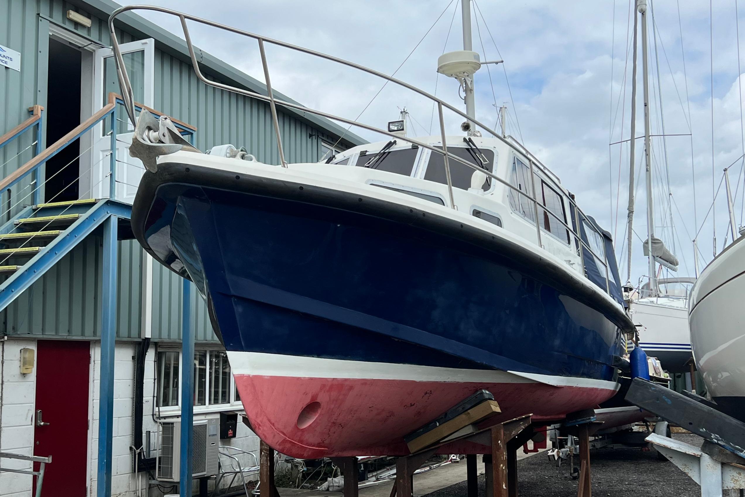Mitchell 31 Mark III 1993 Mitchell 31 Mark III boat on dry dock, blue hull, red bottom, near industrial building.