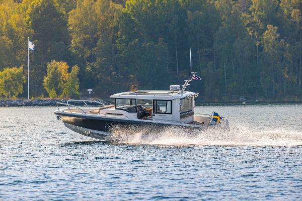 Nimbus C9 Nimbus C9 2025 motorboat cruising on a scenic lake with forested background.