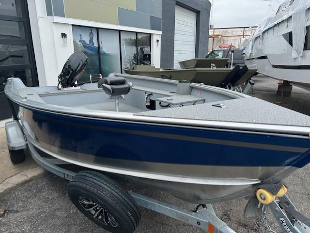 Lund 1675 Alaskan Tiller 2025 Lund 1675 Alaskan Tiller boat on trailer, parked outside a showroom.