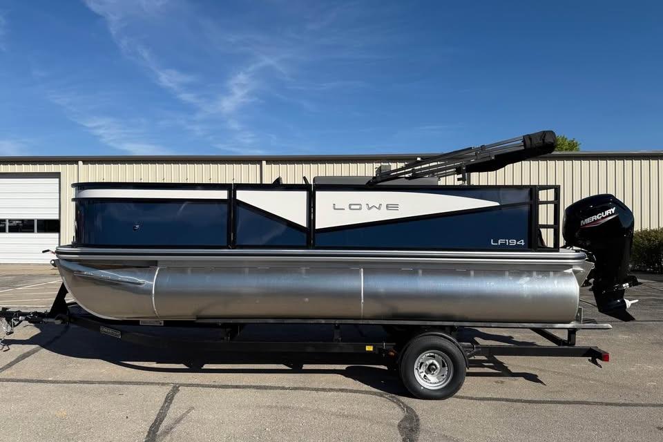 Lowe LF 194 2026 Lowe LF 194 pontoon boat on trailer, parked outdoors under clear blue sky.