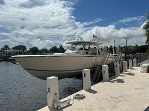 Pursuit 408S Pursuit 408S 2018 boat docked by waterfront under cloudy sky.
