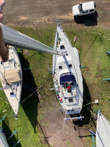Freedom 45 CC Aerial view of a 1989 Freedom 45 CC sailboat on land, with nearby vehicles and greenery.